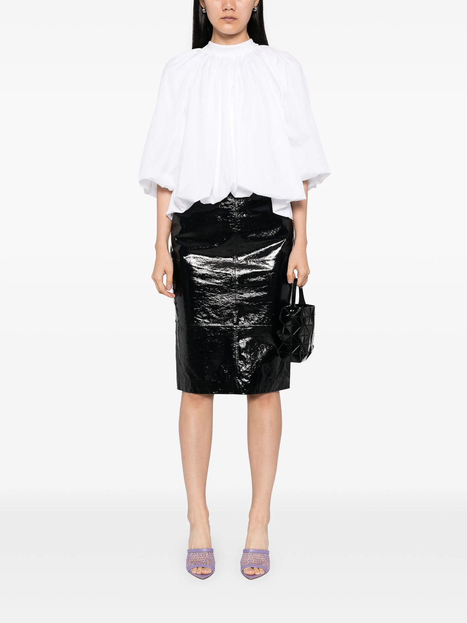 Person wearing a white blouse and black shiny skirt on a white background