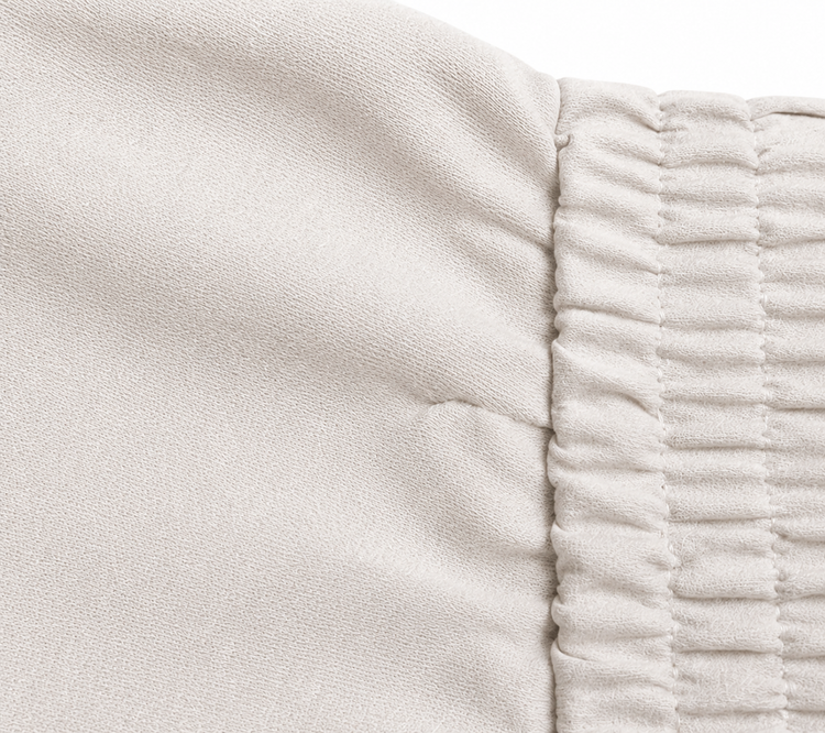 Brunello Cucinelli ivory jogger pants with elasticated drawstring waistband, brown side stripe panels, metallic trim detail, tapered leg, rolled cuffs, and relaxed tailored fit.