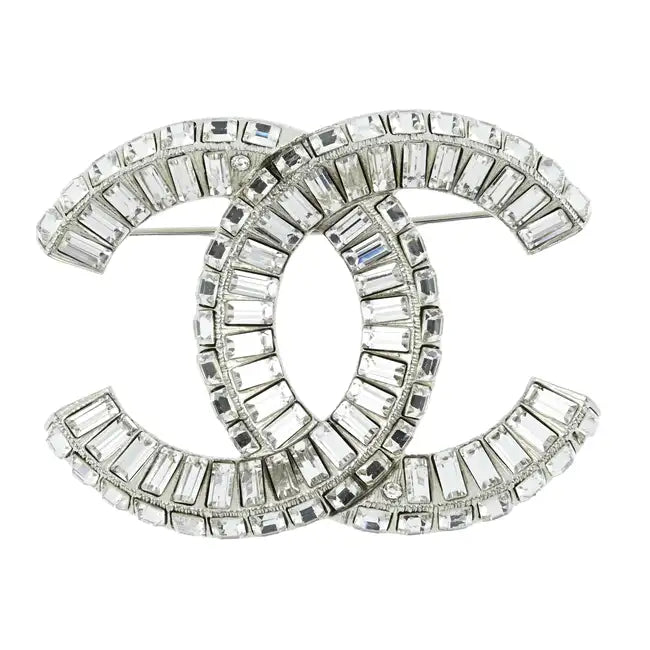 Elegant Chanel crystal brooch pin with intricate design, featuring sparkling crystals on a polished metal setting.