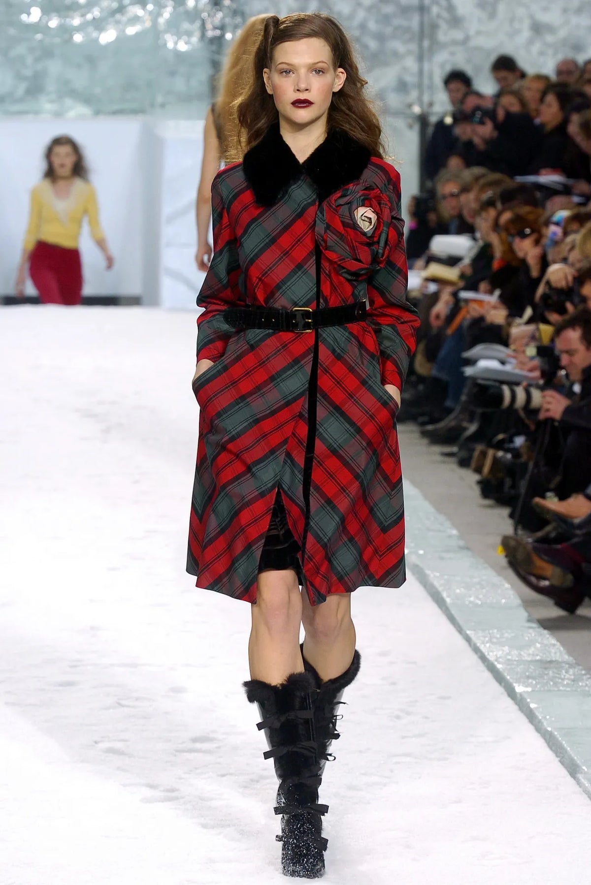 Louis Vuitton 2004 Marc Jacobs tartan trench coat in red, green and black check with plush black collar, long silhouette and oversized rosette appliqué.