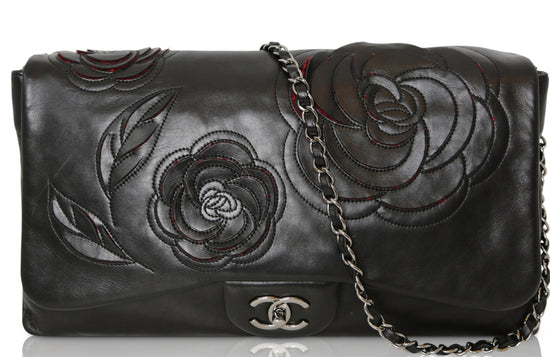 Black lambskin Chanel Camellia Runway Flap Bag with shoulder strap and signature floral detail, stylish and luxurious.
