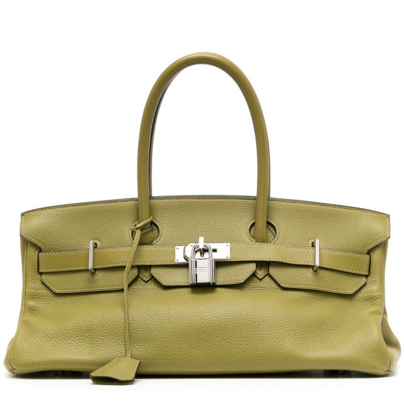 A green leather Birkin bag with two rolled top handles, a foldover top, and metal feet.