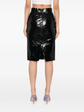 Black patent leather skirt worn by a person on a white background