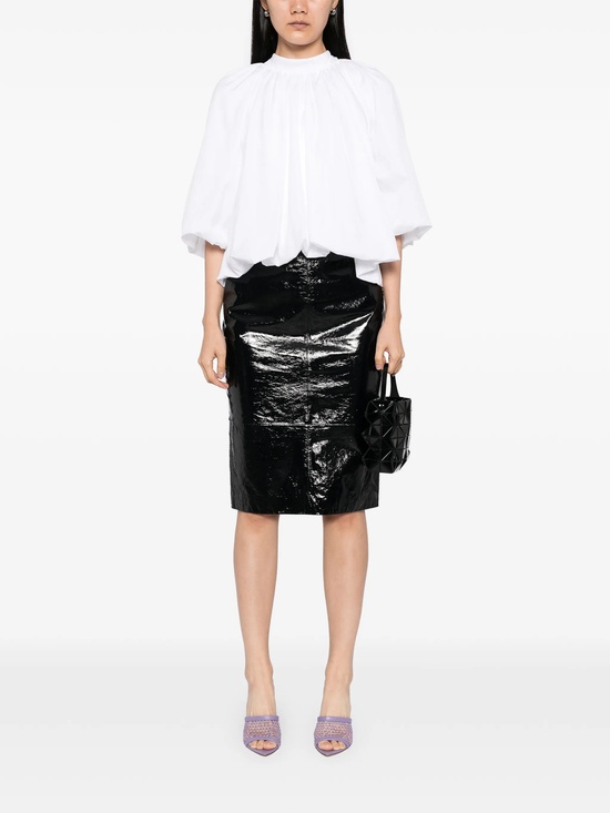 Person wearing a white blouse and black shiny skirt on a white background
