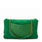 A green quilted suede shoulder bag with a silver-tone chain strap, shown from the back on a white background.