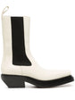 Bottega Veneta two-tone Western ankle boots in ivory leather with black elastic side panels, sculptural black sole, angled heel and rear pull tab.