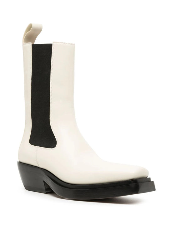 Bottega Veneta two-tone Western ankle boots in ivory leather with black elastic side panels, sculptural black sole, angled heel and rear pull tab.