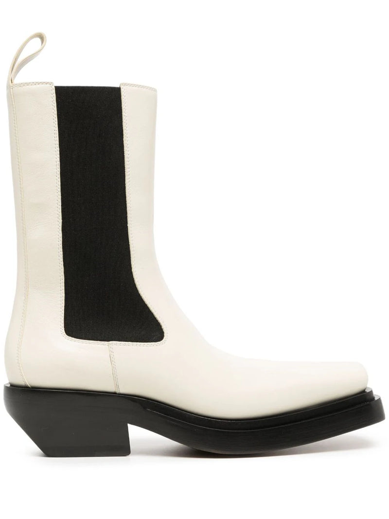 Bottega Veneta two-tone Western ankle boots in ivory leather with black elastic side panels, sculptural black sole, angled heel and rear pull tab.