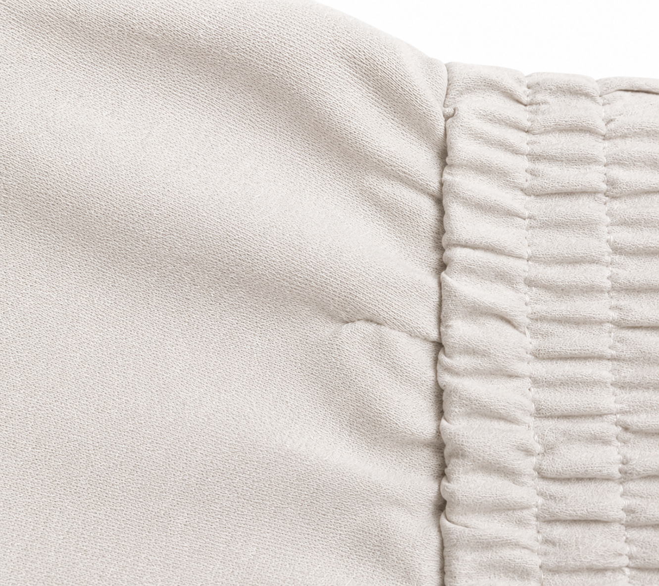 Brunello Cucinelli ivory jogger pants with elasticated drawstring waistband, brown side stripe panels, metallic trim detail, tapered leg, rolled cuffs, and relaxed tailored fit.