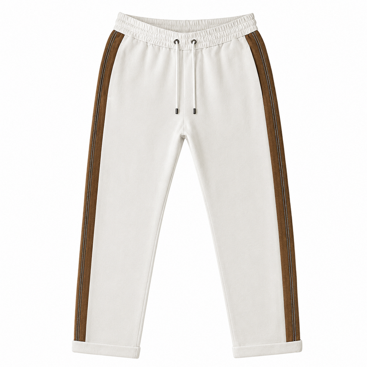 Brunello Cucinelli ivory jogger pants with elasticated drawstring waistband, brown side stripe panels, metallic trim detail, tapered leg, rolled cuffs, and relaxed tailored fit.