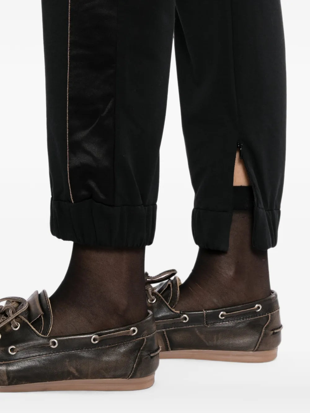 Black Brunello Cucinelli jogger trousers shown on a model, featuring a relaxed fit with elastic waistband and tapered cuffs.