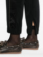 Black Brunello Cucinelli jogger trousers shown on a model, featuring a relaxed fit with elastic waistband and tapered cuffs.