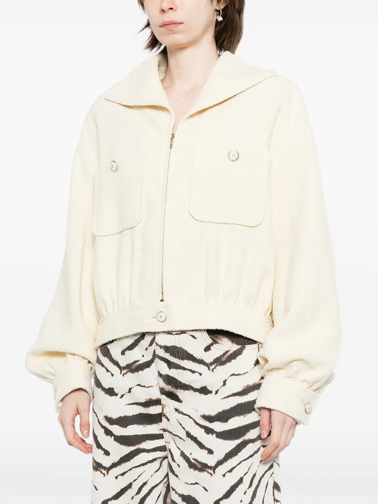 Pre-owned CHANEL tweed jacket with classic pattern, tailored fit, and elegant design, displayed on a hanger.
