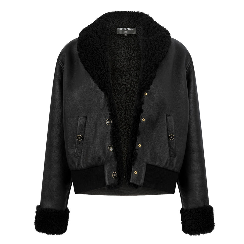 Black leather shearling jacket by Chanel, showing the back view with textured leather and cozy shearling details.