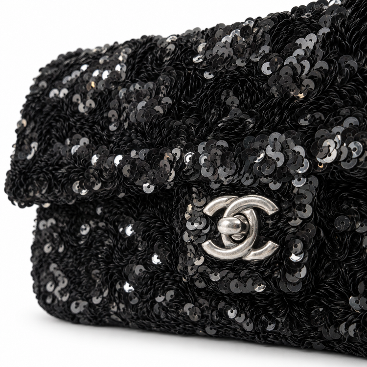 Black Chanel sequin East West flap shoulder bag with gold-tone hardware and chain strap, featuring a quilted design and flap closure.