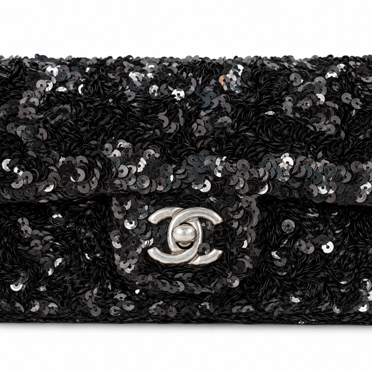 Black Chanel sequin east-west flap shoulder bag with silver hardware and chain strap, stylish and elegant for evening wear.