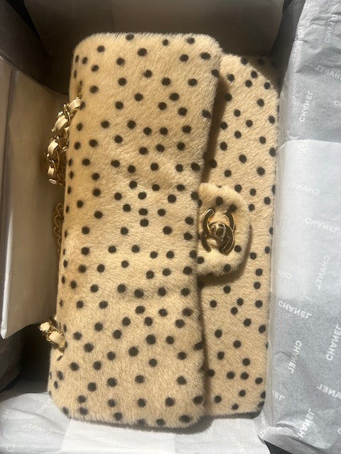 A Chanel "Cheetah Print" Medium Flap Bagshoulder bag in beige fur with black spots, featuring a gold-tone interlocking CC clasp and chain strap, resting inside its branded packaging box with tissue paper.
