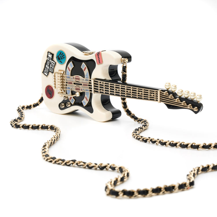 Chanel Collectible Guitar Minaudière Clutch Bag in white and black plexiglass with guitar-shaped design, CC logo detail, sticker-style motifs, pearl embellishment, gold-tone hardware, and chain shoulder strap.