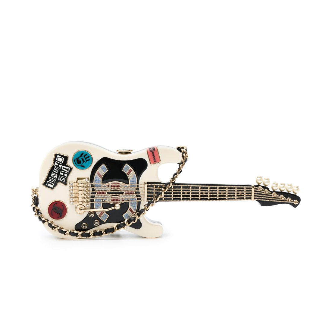 Chanel Collectible Guitar Minaudière Clutch Bag in white and black plexiglass with guitar-shaped design, CC logo detail, sticker-style motifs, pearl embellishment, gold-tone hardware, and chain shoulder strap.
