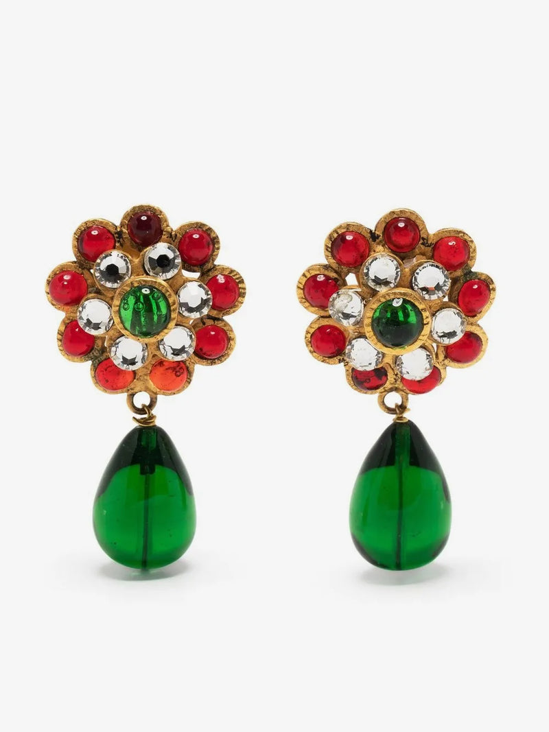 A pair of Chanel Gripoix glass-bead drop earrings, close-up of crystal embellishments featuring a floral cluster top with red, green, and clear rhinestones, and a dangling green teardrop bead below, set against a plain light gray background.