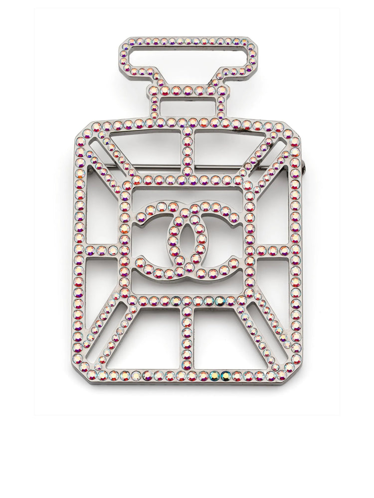 Iridescent Chanel perfume bottle brooch with CC logo, decorative jewelry accessory, shiny glass-like finish, detailed design.