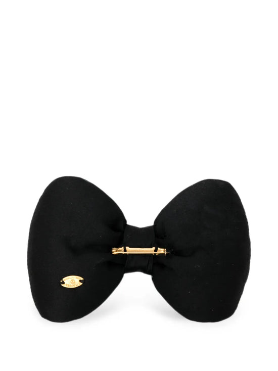 Chanel satin bow brooch with elegant design, featuring a smooth satin finish and decorative bow shape on a plain background.