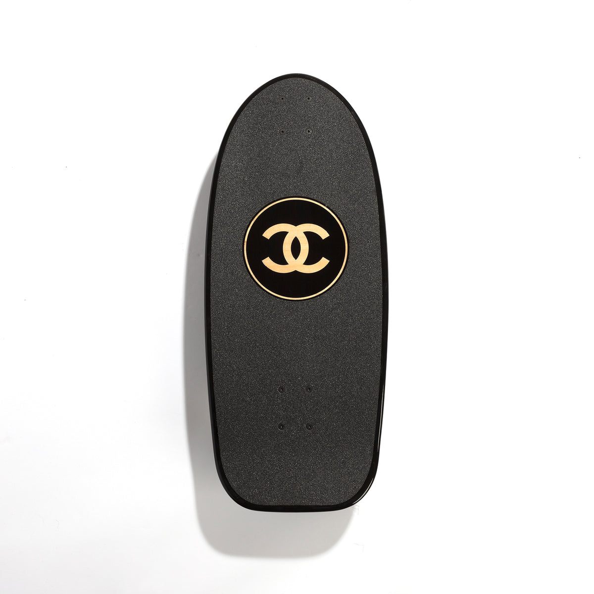 Chanel black skateboard deck with textured grip surface and large gold interlocking CC logo at the centre.