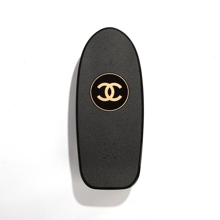 Chanel black skateboard deck with textured grip surface and large gold interlocking CC logo at the centre.