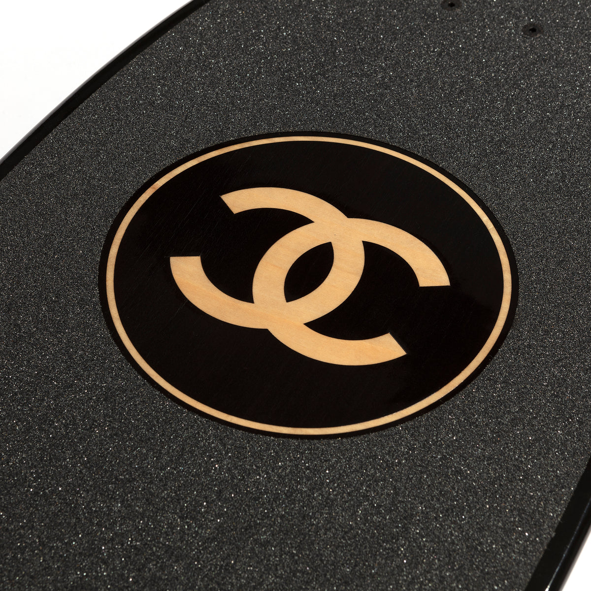 Chanel black skateboard deck with textured grip surface and large gold interlocking CC logo at the centre.