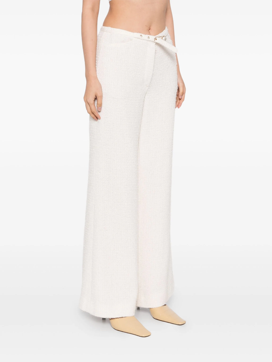 Cream Chanel tweed trousers featuring classic tailored design and textured fabric, displayed on a neutral background.