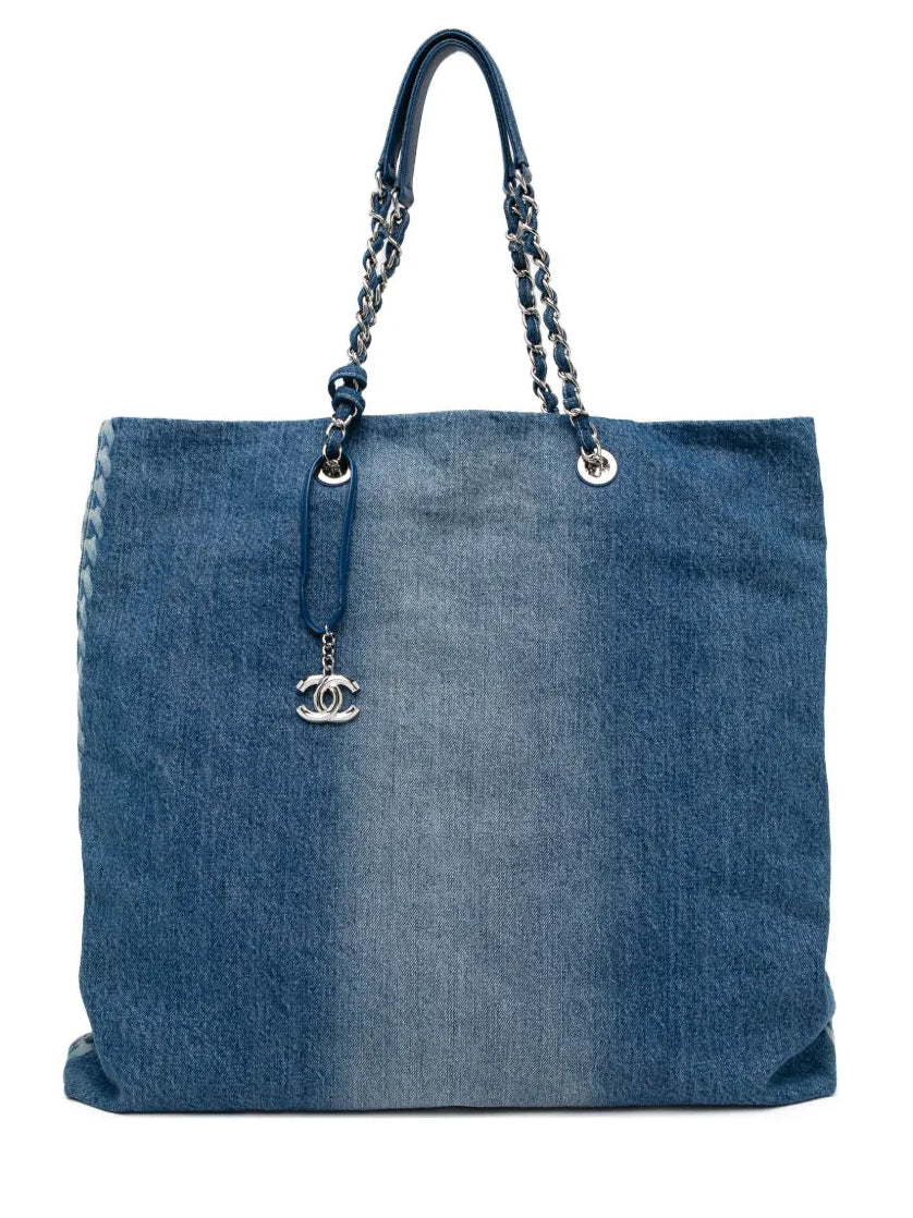 Chanel blue denim shopper bag with chain-and-denim shoulder straps, silver-tone CC charm, faded denim finish and rear quilted pocket with logo plaque.