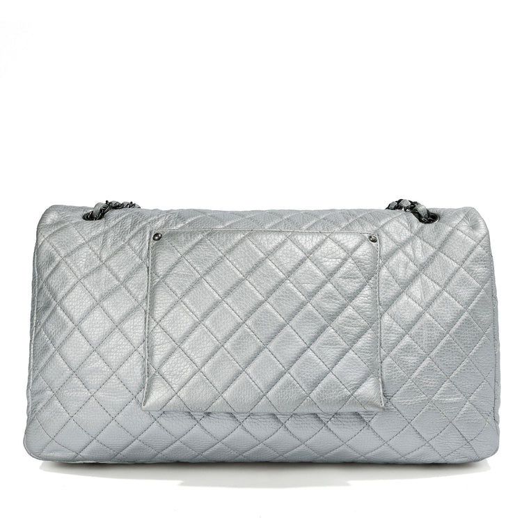 Back view of a metallic silver Chanel XXL airline travel flap bag with shoulder strap, showcasing sleek design and spacious interior.