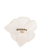 Chanel off-white fabric camellia flower brooch pin featuring layered petals and a leaf accent with a subtle cream CC logo.