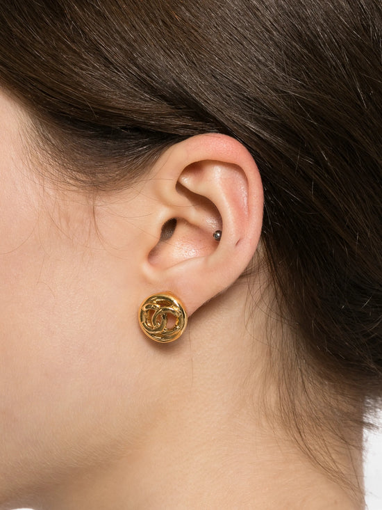 Chanel small gold emblem clip-on earrings featuring a classic brand logo design on a plain background.