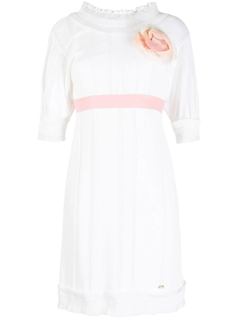 Chanel white babydoll dress with pale pink waistband, camellia flower embellishment, high ruffled neckline, short sleeves and pleated trim detailing.