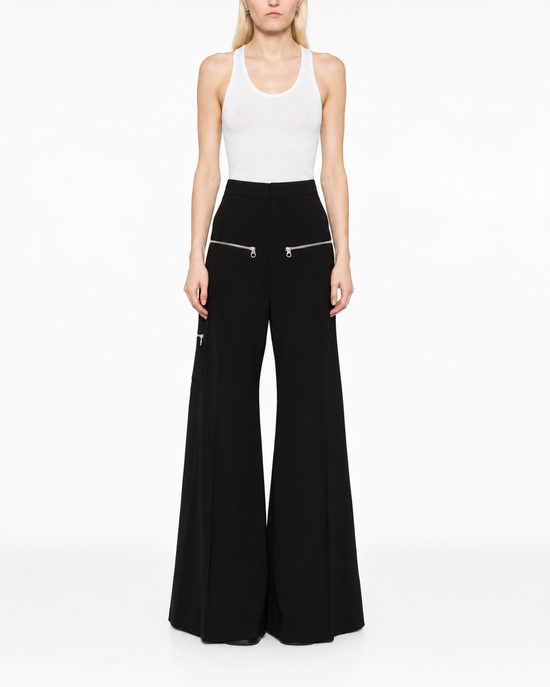 Chloé flared zip trousers featuring high waist, wide leg design, and front zipper detail, shown in a stylish fashion photograph.