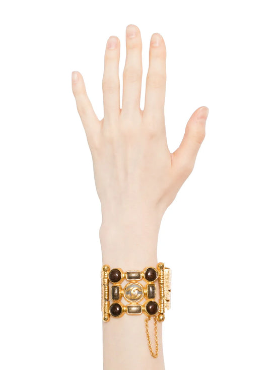 Vintage Chanel wide gold-plated cuff bracelet featuring amber Gripoix glass cabochons and a central frosted medallion with the interlocking CC logo.