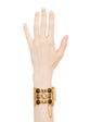 Vintage Chanel wide gold-plated cuff bracelet featuring amber Gripoix glass cabochons and a central frosted medallion with the interlocking CC logo.