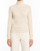 A model wearing a light beige turtleneck sweater and matching cream trousers, shown from the neck down against a plain white background. Hermès Beige Cashmere Turtleneck