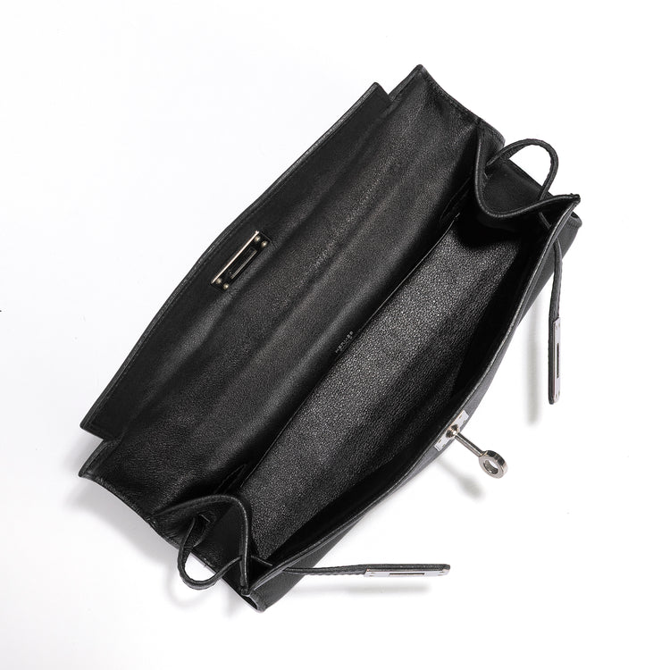Hermès Kelly Pochette in black Swift leather, showing the interior of the elegant handbag with gold hardware accents.