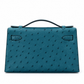 Hermès Kelly Pochette in Bleu Colvert ostrich leather with gold hardware, showcasing a luxurious handbag with elegant stitching and texture.