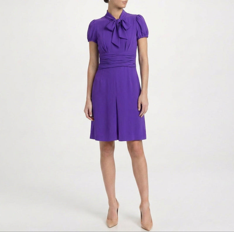 Purple Prada short-sleeve dress with a fitted bodice and flowing skirt, displayed on a hanger against a neutral background.