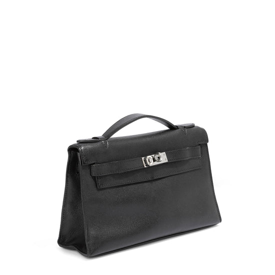 Side view of Hermès Kelly Pochette in black Swift leather, showcasing its elegant top handle design and sleek stitching details.