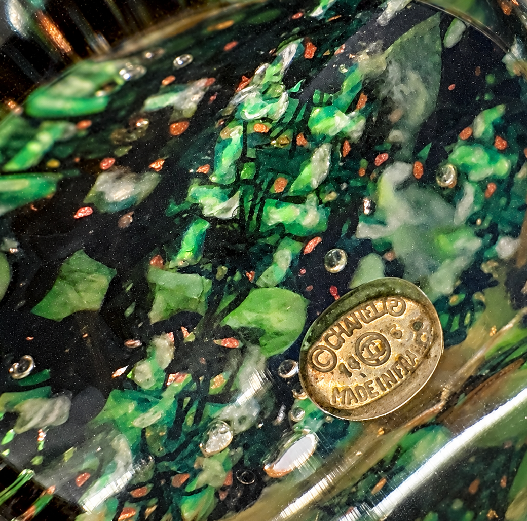 Green tweed Chanel ring with marbled interior and brass plaque, showcasing elegant craftsmanship and textured design.