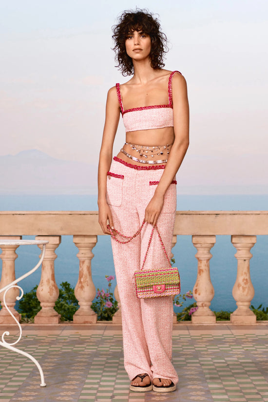 Pink tweed Chanel trousers displayed on a model, showcasing the stylish and textured fabric of the elegant fashion piece.