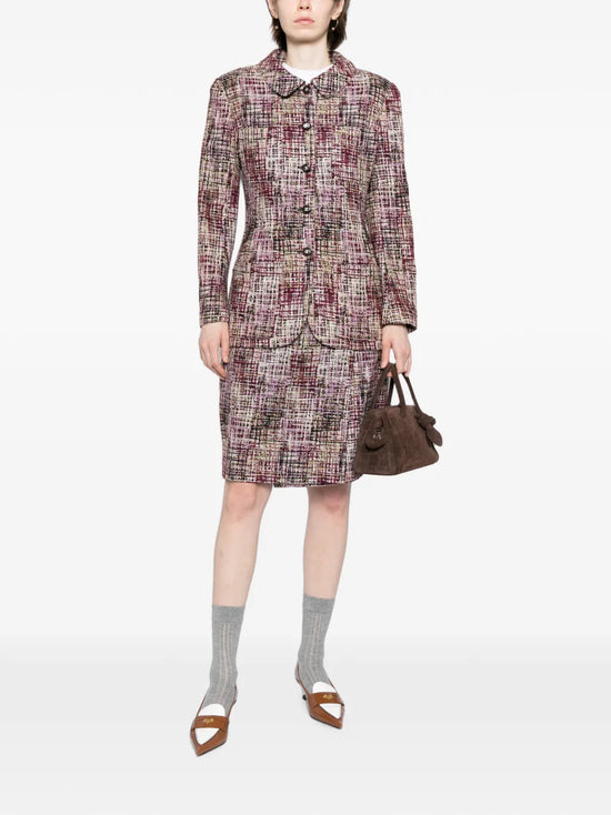 Chanel tweed skirt set featuring a tailored blazer and matching skirt, classic boucle fabric with gold button details.