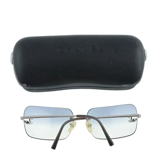 Chanel rimless sunglasses with blue lenses and sleek frame, displayed with their box on a white background.