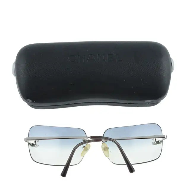 Chanel rimless sunglasses with blue lenses and sleek frame, displayed with their box on a white background.