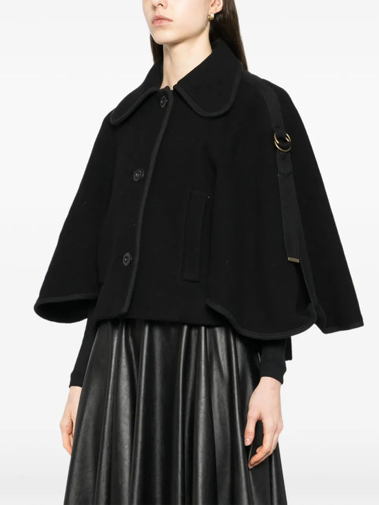 Model wearing a black cape-collar coat by Chloé, showcasing the elegant design and flowing fabric of the stylish outerwear.