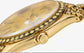 Close-up of a gold-tone wristwatch with a gold dial, a bezel set with small round stones, and a visible Rolex crown logo on the side.